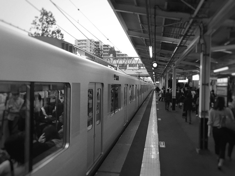 駅のホームに電車が停車しているモノクロ写真