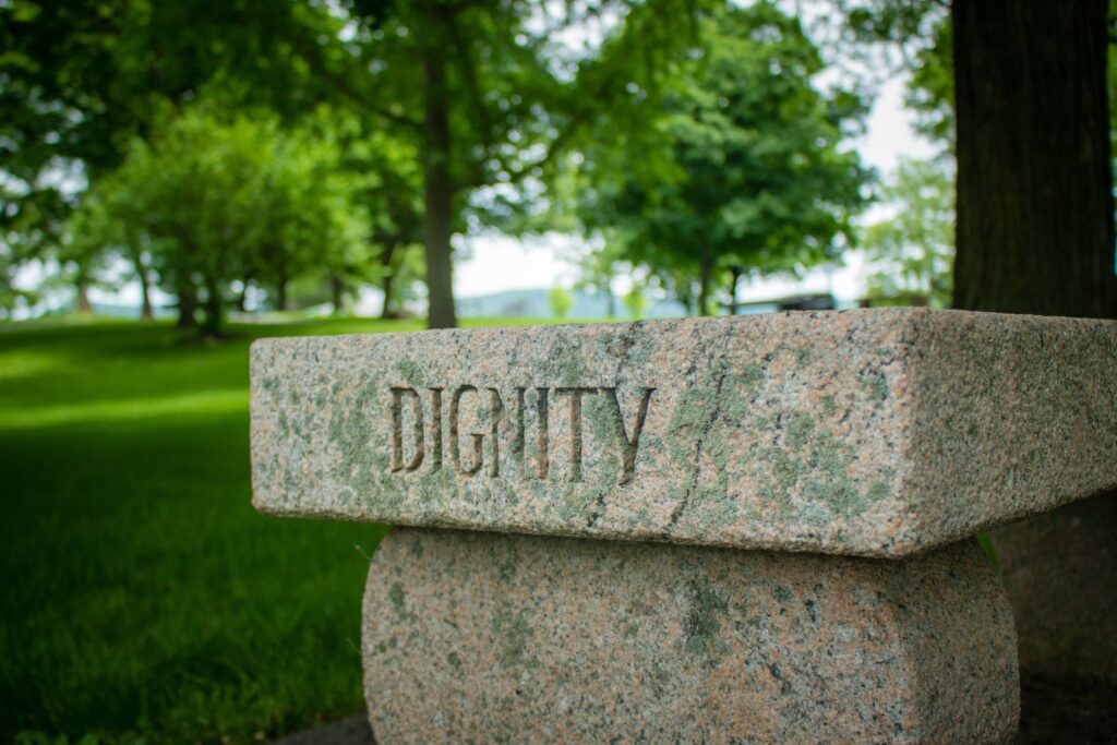 「DIGNITY（尊厳）」と彫られた石が広い公園に設置されている写真