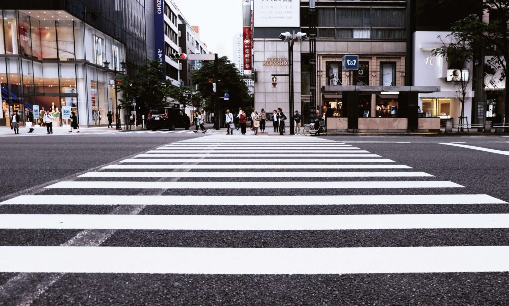 大通りに敷設された横断歩道と信号待ちをしている人々の写真。